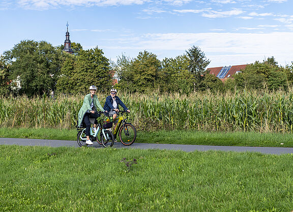 Mann und Frau radeln entlang Maisfeld